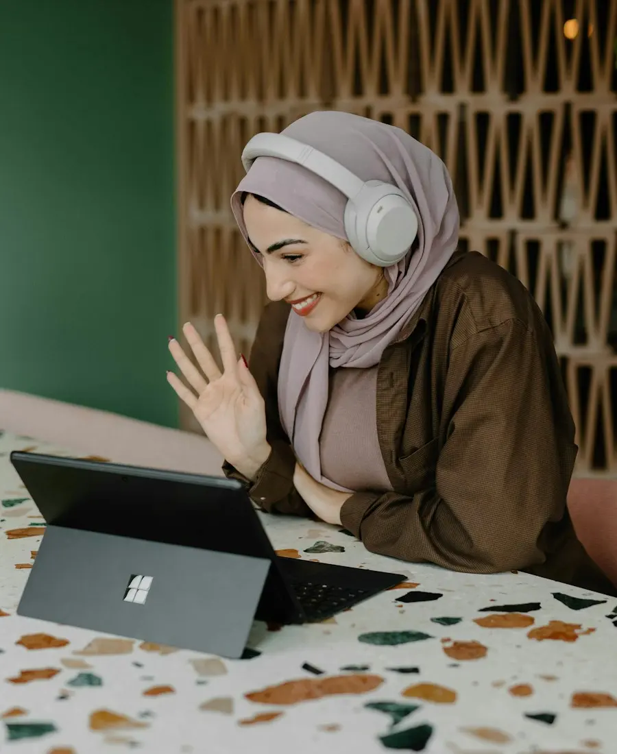 A woman waving hello on a video call.